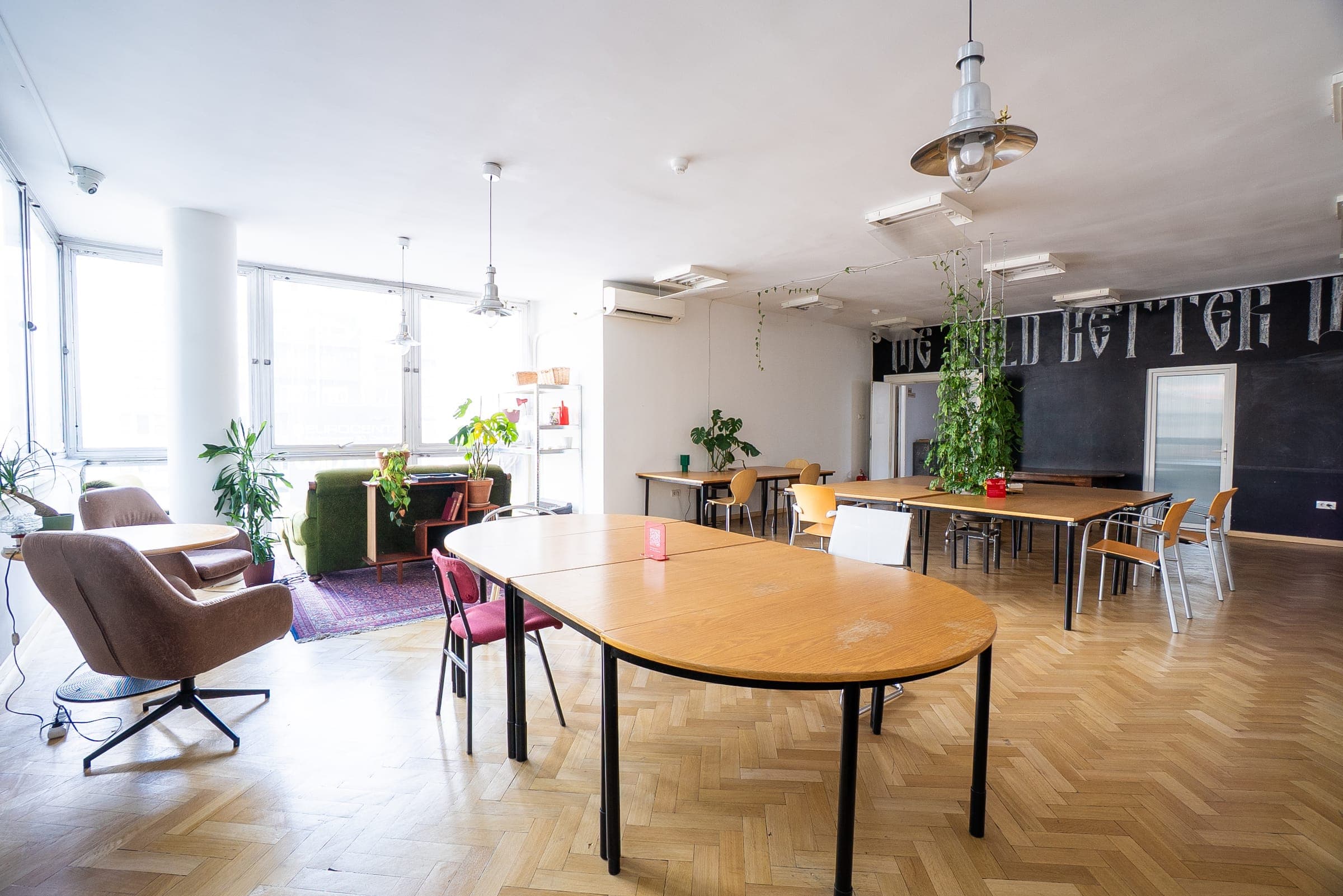 Spacious coworking hall at SENSE—S.SPACE with communal tables, lounge seating, and chalkboard