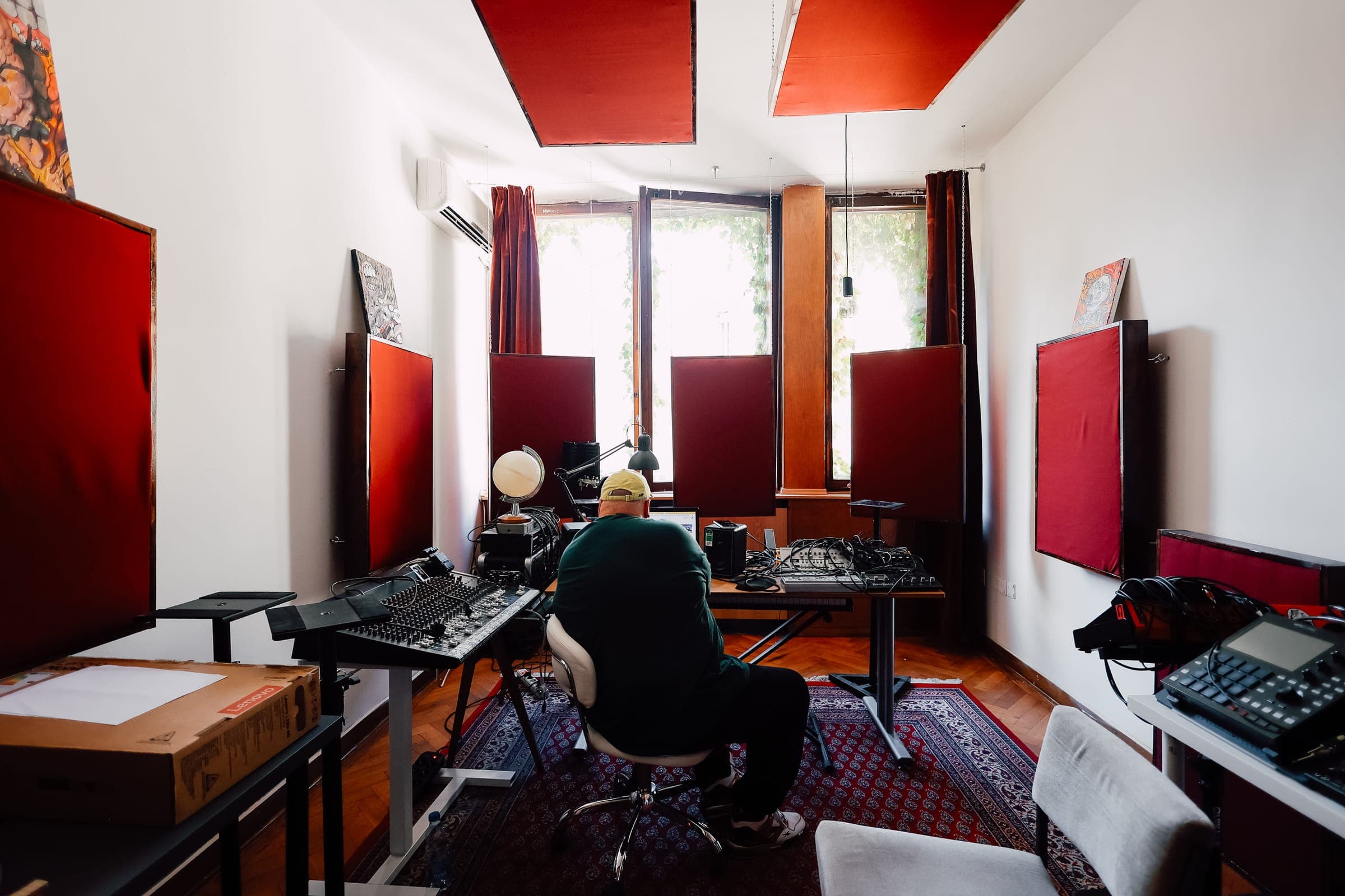 Producer at work in the music studio at SENSE—S.SPACE with mixing console and red acoustic treatment